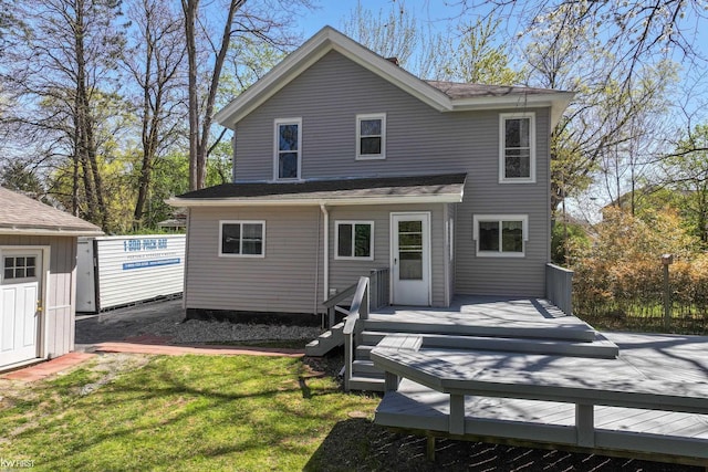 rear view of house with a lawn, an outbuilding, a deck, and a storage shed