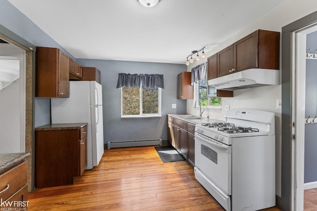 kitchen with a sink, white appliances, light wood-style floors, under cabinet range hood, and a baseboard radiator