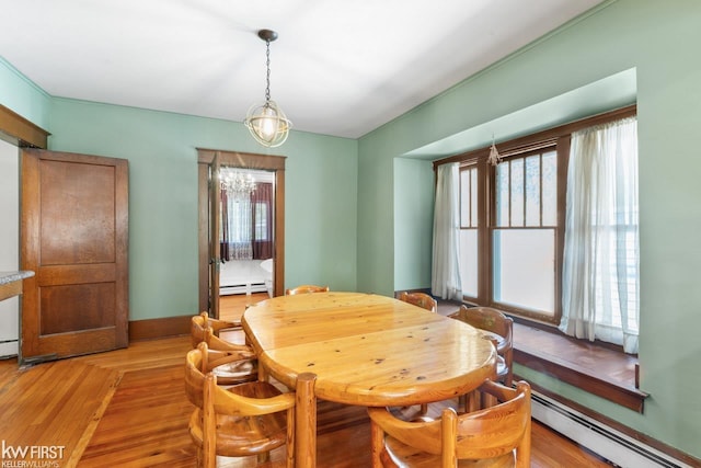 dining space featuring a baseboard radiator, light wood finished floors, and a chandelier