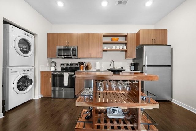 kitchen featuring visible vents, stacked washer and dryer, dark wood-style flooring, light countertops, and stainless steel appliances