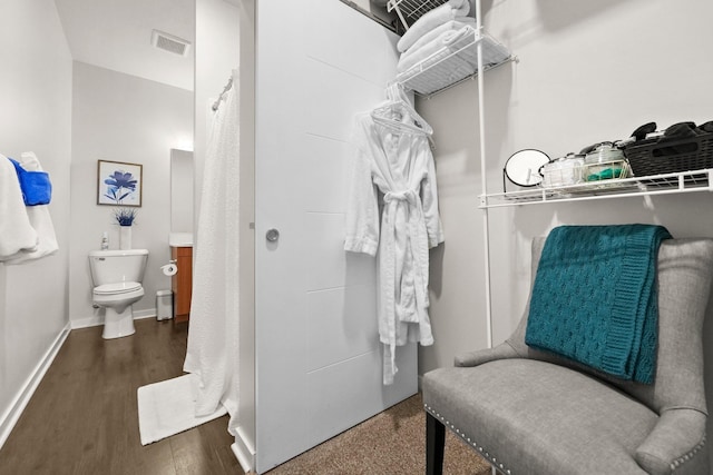 bathroom featuring toilet, baseboards, visible vents, and wood finished floors