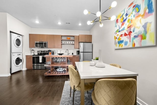 dining space with visible vents, dark wood finished floors, stacked washing maching and dryer, a notable chandelier, and recessed lighting