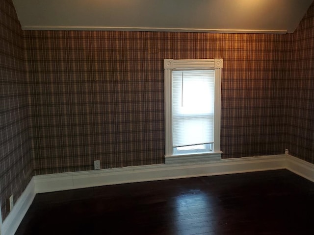 429 S Arnold, Mount Pleasant, MI 48858 - empty room featuring wallpapered walls, vaulted ceiling, baseboards, and hardwood / wood-style floors