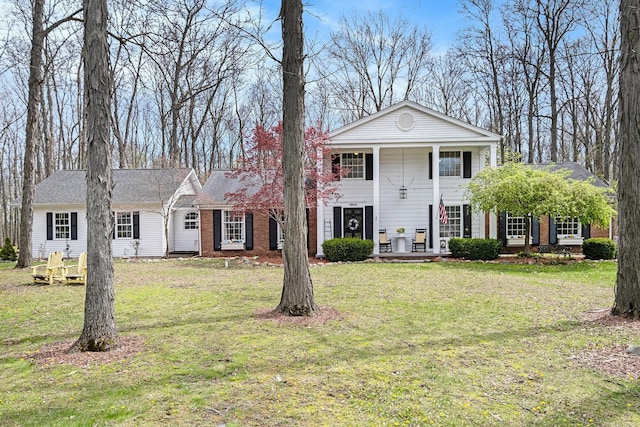 neoclassical home with a porch, brick siding, and a front lawn