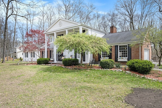 greek revival inspired property with covered porch, a chimney, brick siding, a front lawn, and a shingled roof