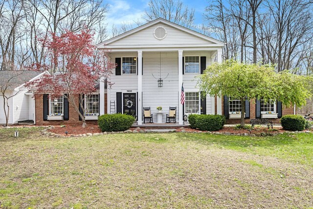 view of front of home with a porch, brick siding, and a front yard
