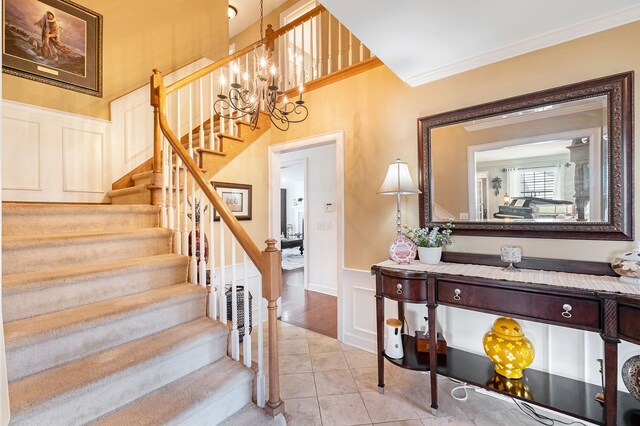 stairway with a wainscoted wall, ornamental molding, a decorative wall, and tile patterned floors