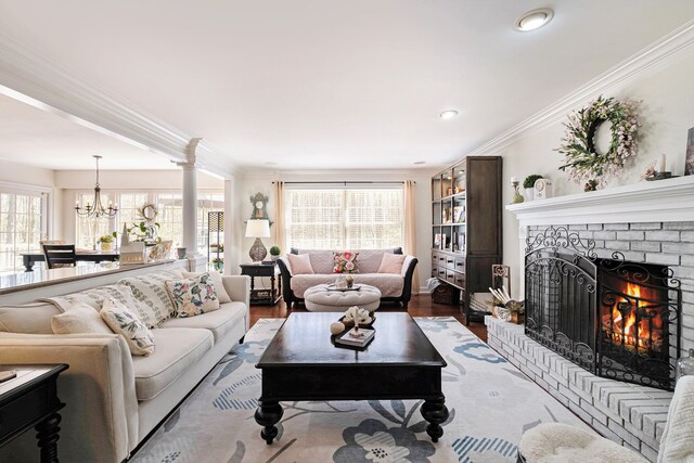 living area with a notable chandelier, a brick fireplace, recessed lighting, wood finished floors, and ornamental molding
