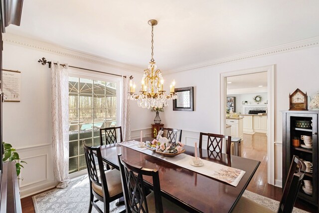 dining room featuring a notable chandelier, wainscoting, wood finished floors, and a decorative wall