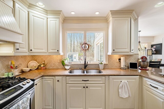 kitchen featuring decorative backsplash, stainless steel range with gas stovetop, light stone countertops, a sink, and custom range hood