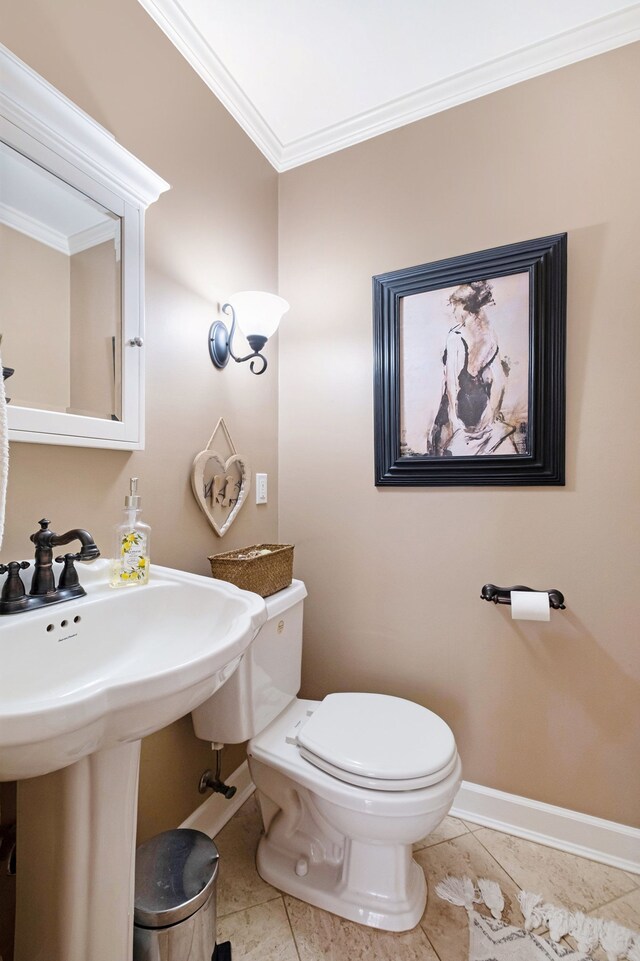 bathroom with crown molding, toilet, and baseboards