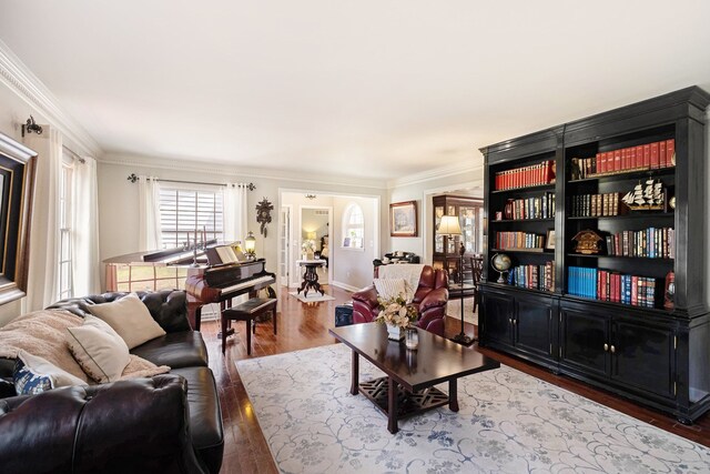 living room featuring crown molding, baseboards, and wood finished floors