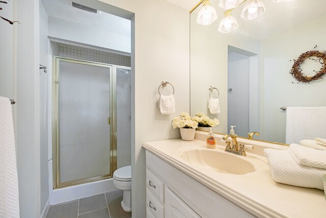 bathroom with visible vents, tile patterned flooring, a stall shower, vanity, and toilet