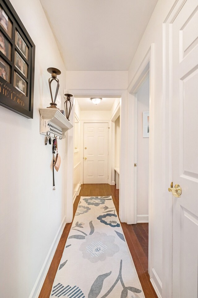 hall with dark wood-style flooring and baseboards