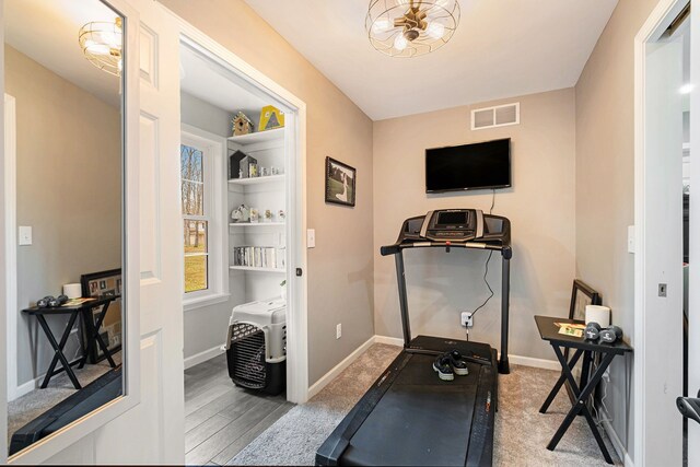 exercise area with baseboards, wood finished floors, and visible vents