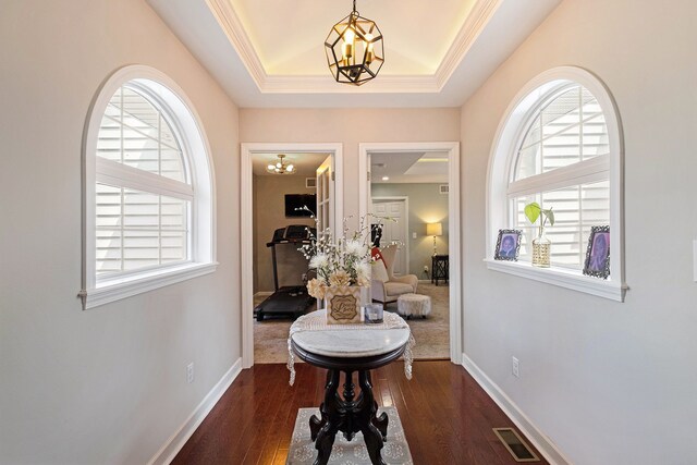 hallway with an inviting chandelier, plenty of natural light, dark wood finished floors, and visible vents