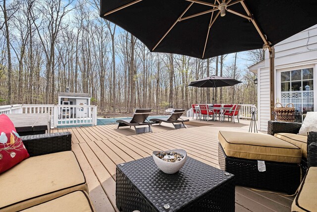 wooden terrace with outdoor dining area, an outdoor structure, a shed, and an outdoor living space