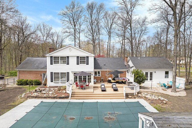 rear view of property with a wooden deck, a chimney, a covered pool, and outdoor lounge area