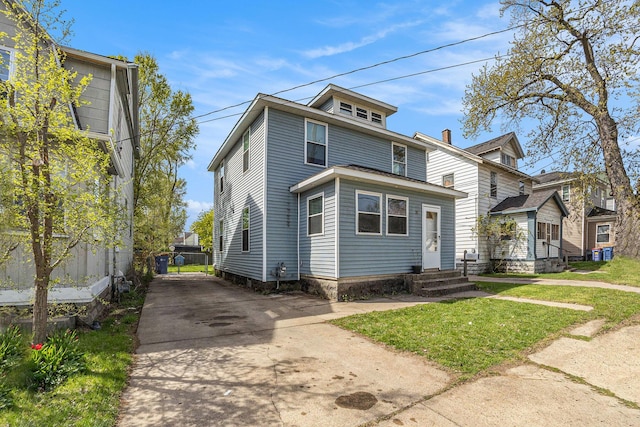 american foursquare style home featuring fence, driveway, and a front yard