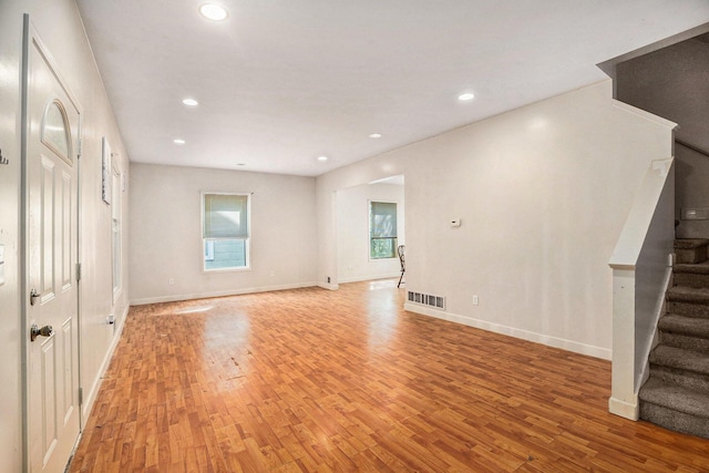 unfurnished living room with light wood-style floors, stairs, recessed lighting, baseboards, and visible vents