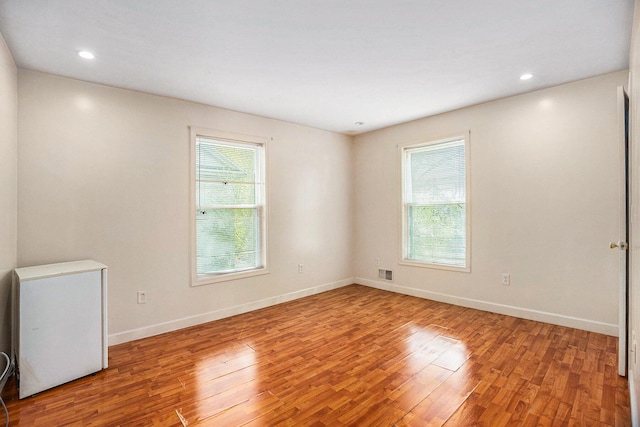 unfurnished room with a healthy amount of sunlight, baseboards, and wood finished floors