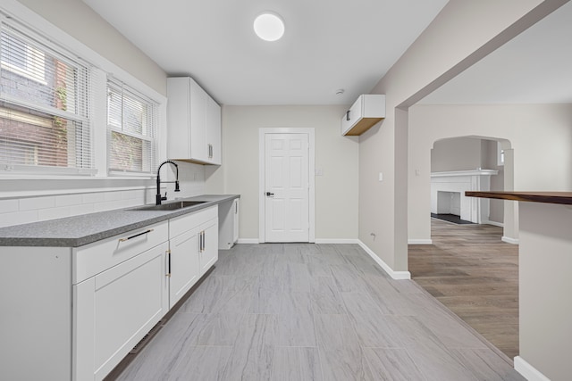 15866 Woodingham Dr, Detroit, MI 48238 - kitchen featuring a sink, arched walkways, light wood-style flooring, and white cabinetry