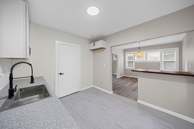 15866 Woodingham Dr, Detroit, MI 48238 - kitchen with arched walkways, a sink, baseboards, light countertops, and white cabinetry