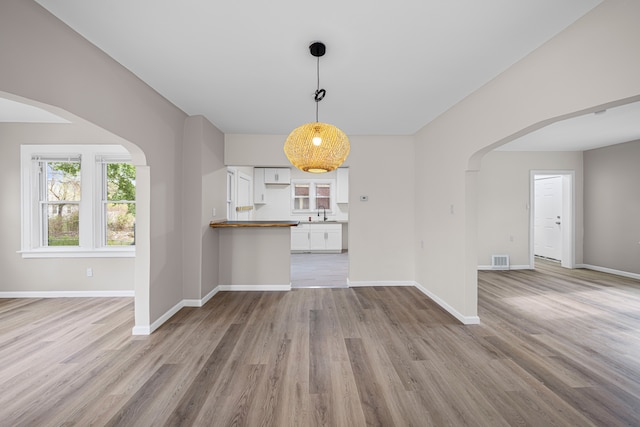 15866 Woodingham Dr, Detroit, MI 48238 - unfurnished living room with arched walkways, baseboards, wood finished floors, and visible vents