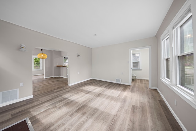 15866 Woodingham Dr, Detroit, MI 48238 - unfurnished living room featuring arched walkways, baseboards, wood finished floors, and visible vents