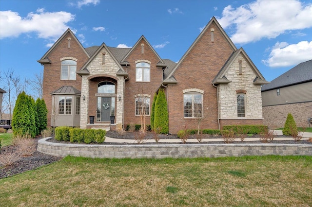 french provincial home with stone siding, brick siding, and a front yard