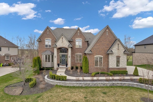 french country home featuring stone siding, a front lawn, and brick siding