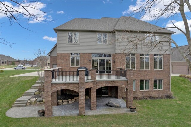 rear view of house featuring a lawn, brick siding, a wooden deck, and a patio area