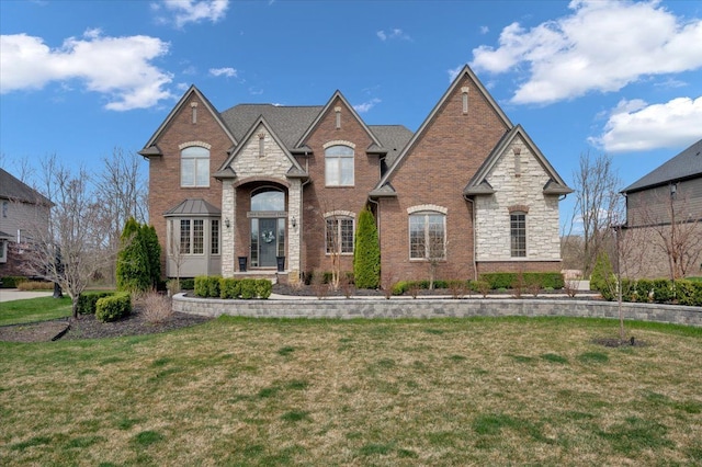french country home with brick siding, stone siding, and a front lawn