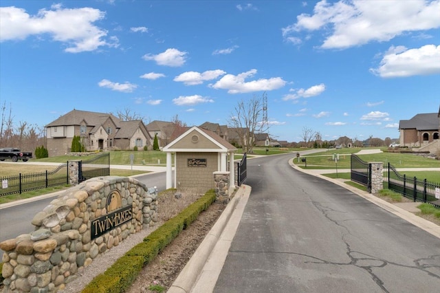 view of street with curbs, a gated entry, and a residential view
