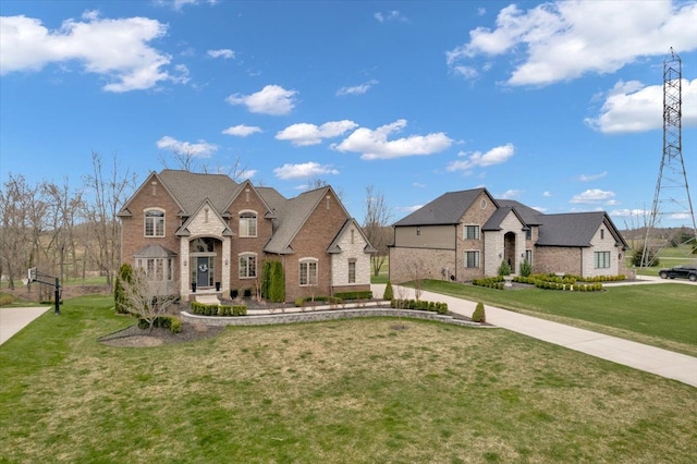 french provincial home with brick siding and a front lawn