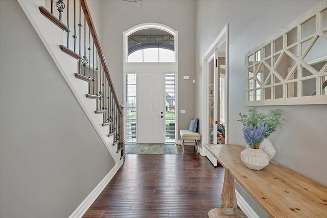 entryway featuring a high ceiling, a wealth of natural light, stairway, and dark wood-style floors