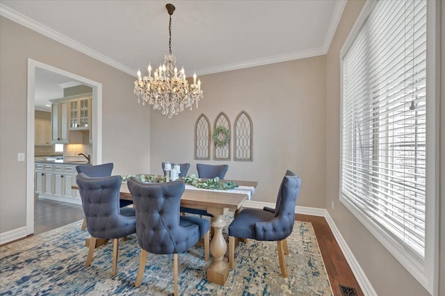 dining space featuring crown molding, dark wood-style flooring, a notable chandelier, baseboards, and visible vents