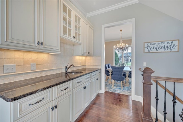 kitchen with a sink, white cabinets, dark stone countertops, a chandelier, and dark wood-type flooring
