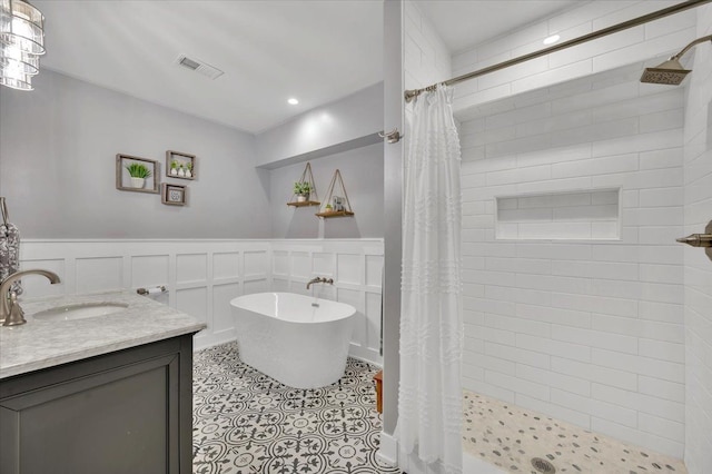 bathroom featuring visible vents, vanity, a freestanding tub, wainscoting, and a stall shower