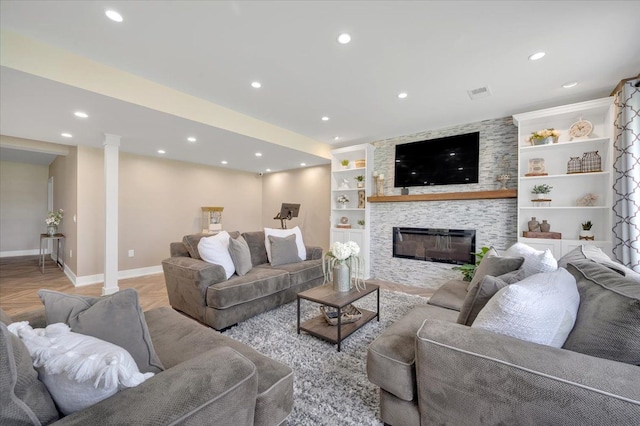 living area with visible vents, baseboards, a stone fireplace, recessed lighting, and built in shelves