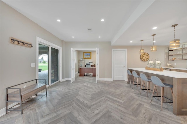 kitchen with light countertops, baseboards, a breakfast bar, and recessed lighting