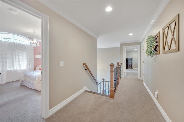 corridor with carpet floors, a notable chandelier, crown molding, and an upstairs landing
