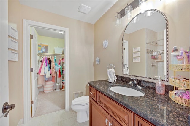 full bathroom featuring a walk in closet, vanity, toilet, baseboards, and visible vents