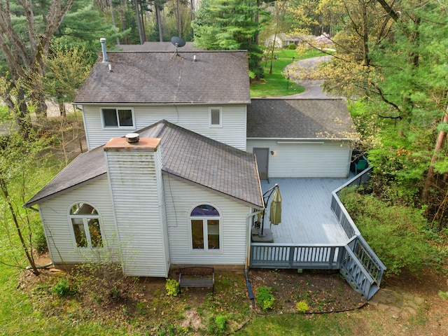 back of house with a shingled roof and a deck