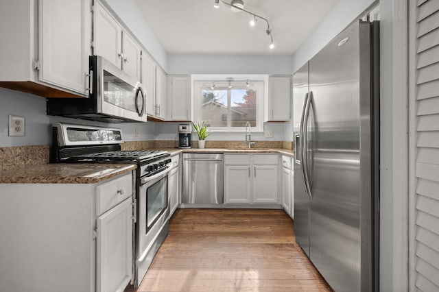 kitchen featuring white cabinets, appliances with stainless steel finishes, a sink, and light wood-style flooring