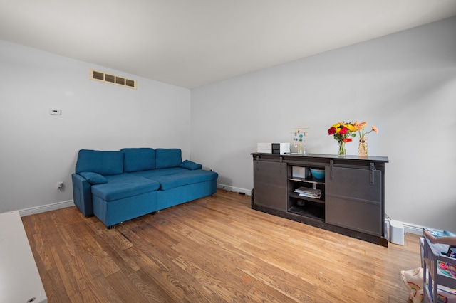 living area with visible vents, light wood-style floors, and baseboards