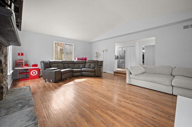 living room with visible vents, lofted ceiling, and light wood finished floors