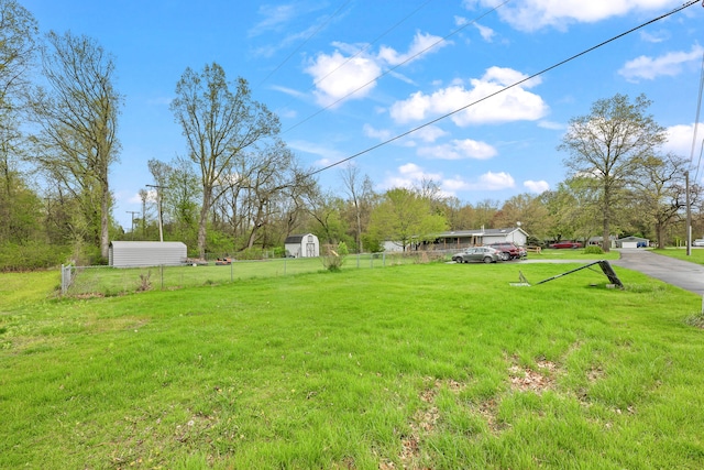view of yard featuring a storage shed, fence, and an outbuilding