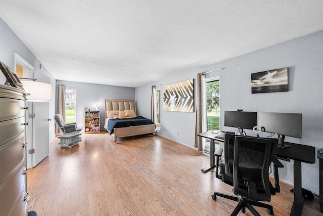 bedroom with a textured ceiling, baseboards, and wood finished floors