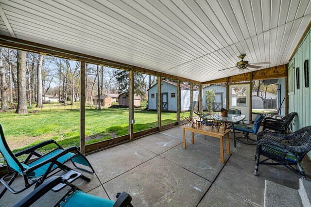 sunroom with a residential view, a ceiling fan, and outdoor dining area